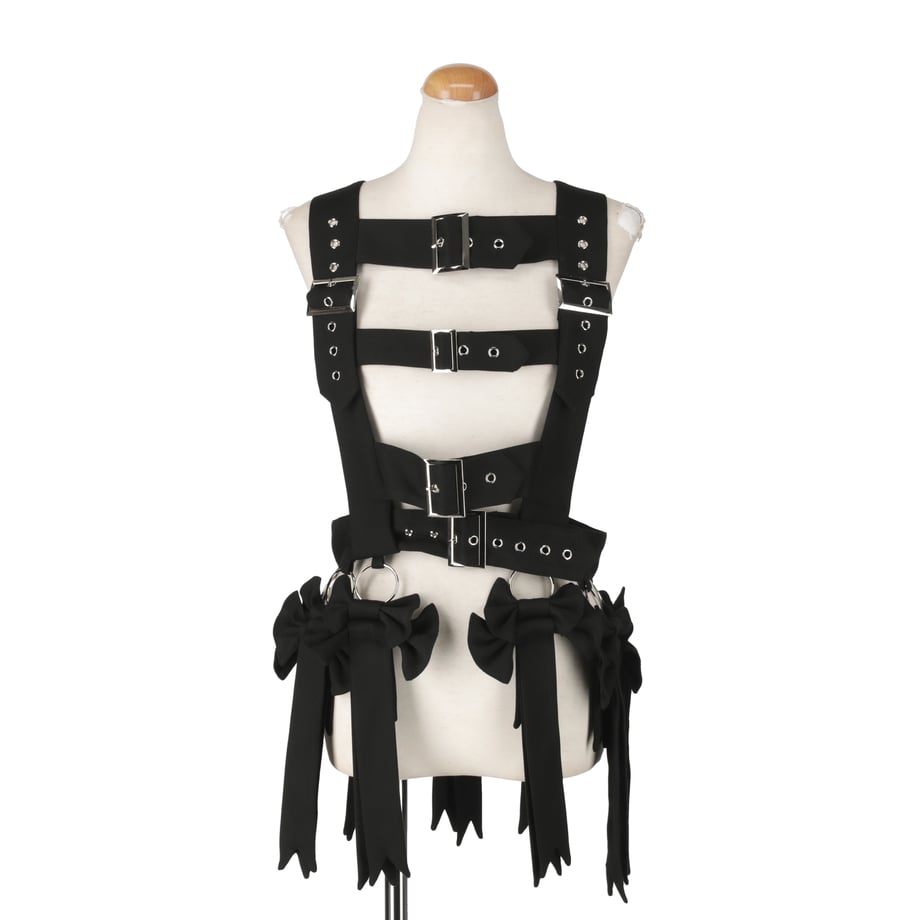 Front view of the black chaos belt harness displayed on a mannequin, showing straps, buckles, rings, and hanging ribbon-like details.