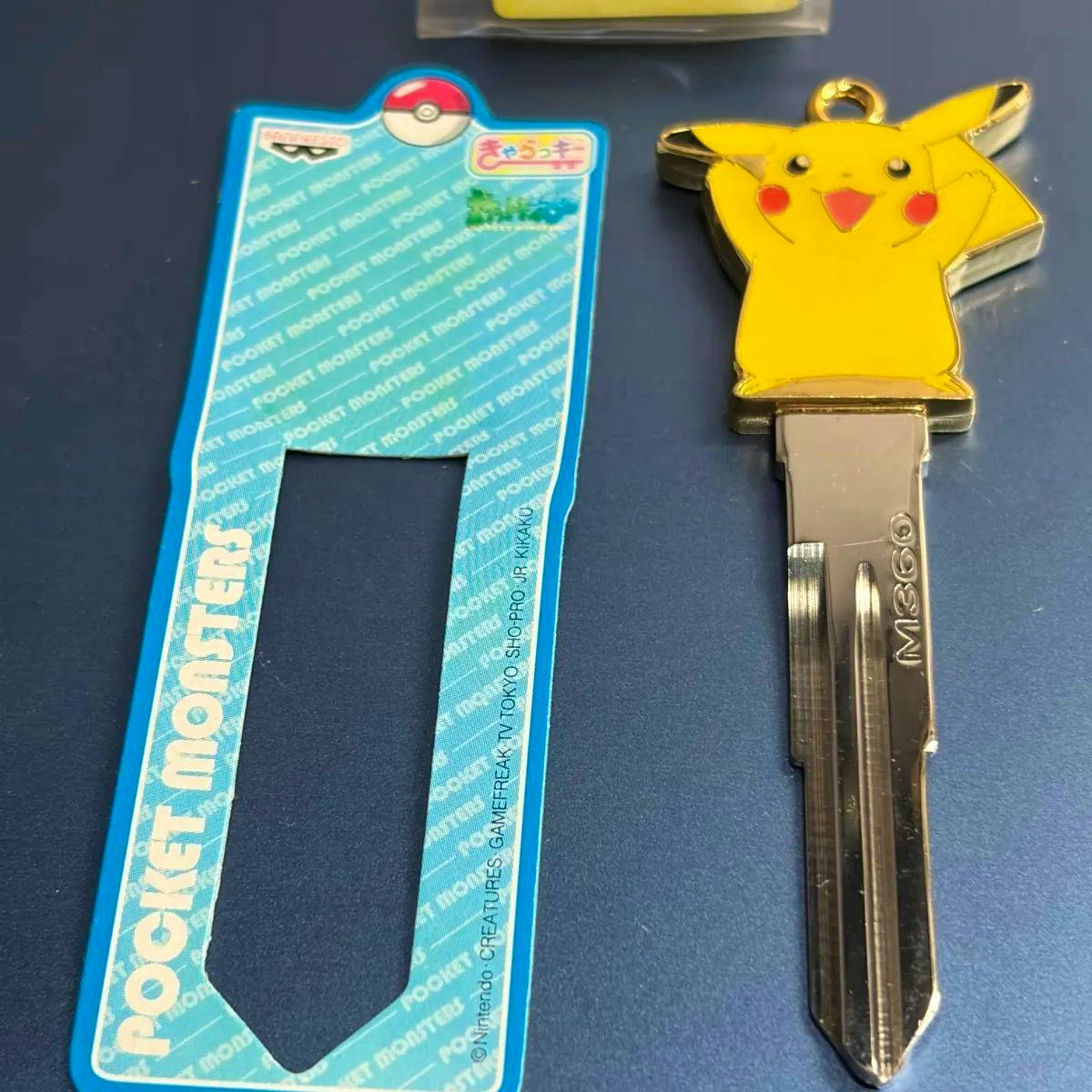 Metal Pikachu car key cover on a key blank stamped "M360", shown next to a blue product backing card.