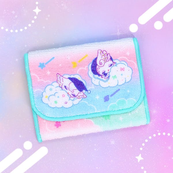 Folded polyester pocket hand towel with character designs of sleeping figures on clouds and turquoise edging.