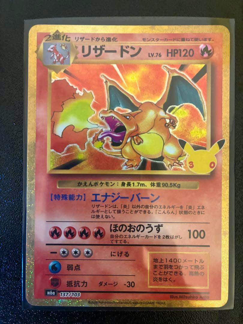 Photograph of a Japanese Charizard (リザードン) trading card with a gold border and holographic foil.