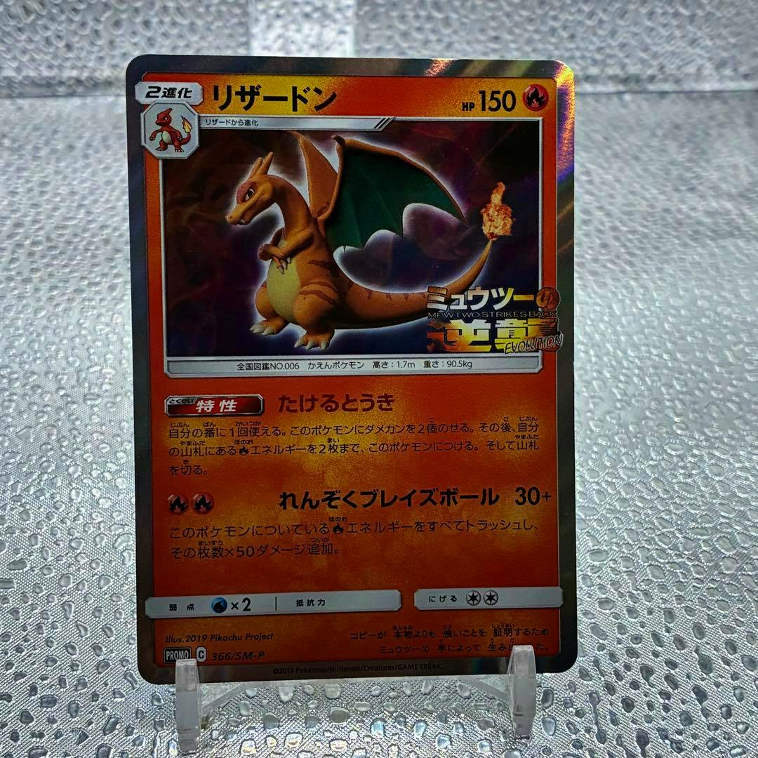 Front of a Charizard (リザードン) Pokémon trading card promo for Mewtwo Strikes Back displayed upright on a clear plastic stand.