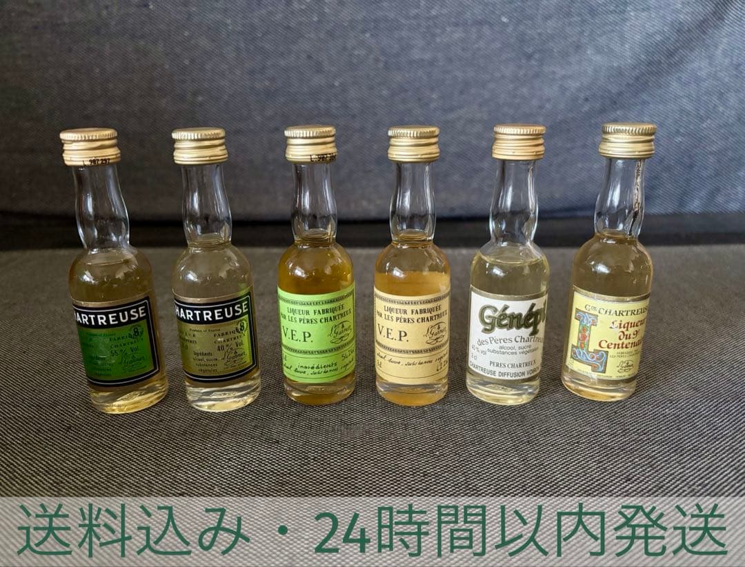 Six unopened Chartreuse mini bottles (6-piece set) arranged in a row on a gray fabric surface.