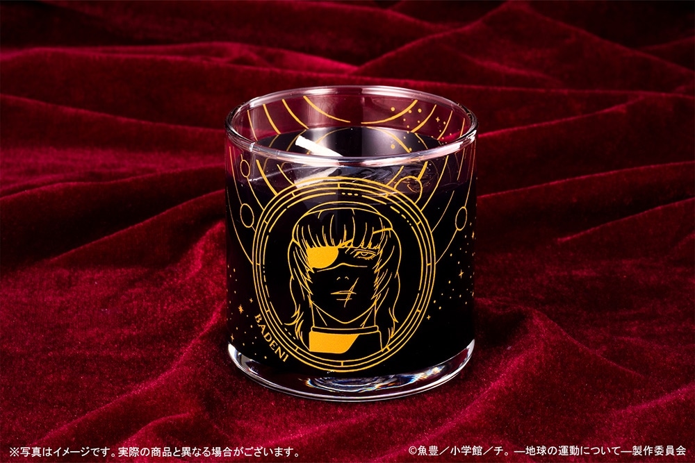 A glass gel candle (『チ。 ―地球の運動について―』星空ジェルキャンドル バデーニ) with a gold line-art character illustration on dark blue gel, photographed on a red velvet background.