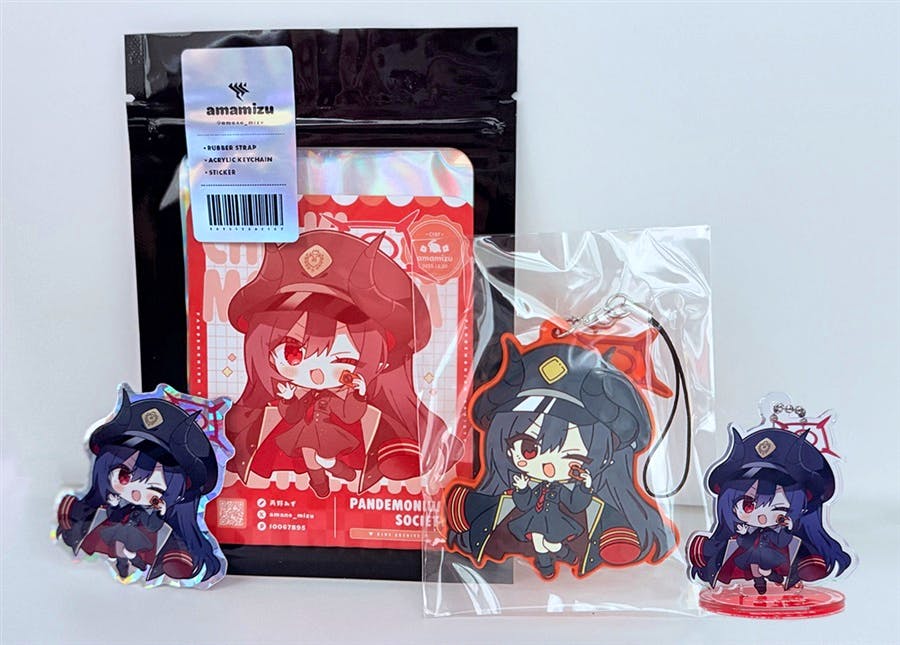 Photo of the Chiaki goods set laid out, showing a packaged rubber strap, an acrylic keychain in plastic, a small acrylic stand, and the backing card in a resealable bag.