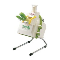 White vegetable slicer on metal legs with green onions inserted into the feed chute.