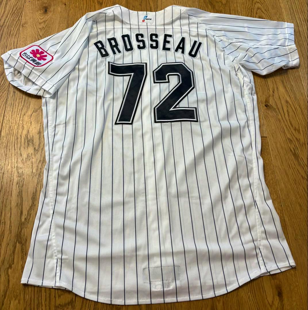Back of a white pinstriped Chiba Lotte Marines baseball jersey showing the name BROSSEAU and number 72 laid on a wooden floor.