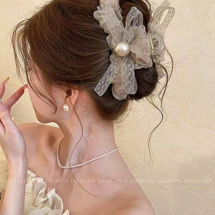 Side view of a woman wearing a chiffon ribbon hair clip with lace bow and a central pearl.