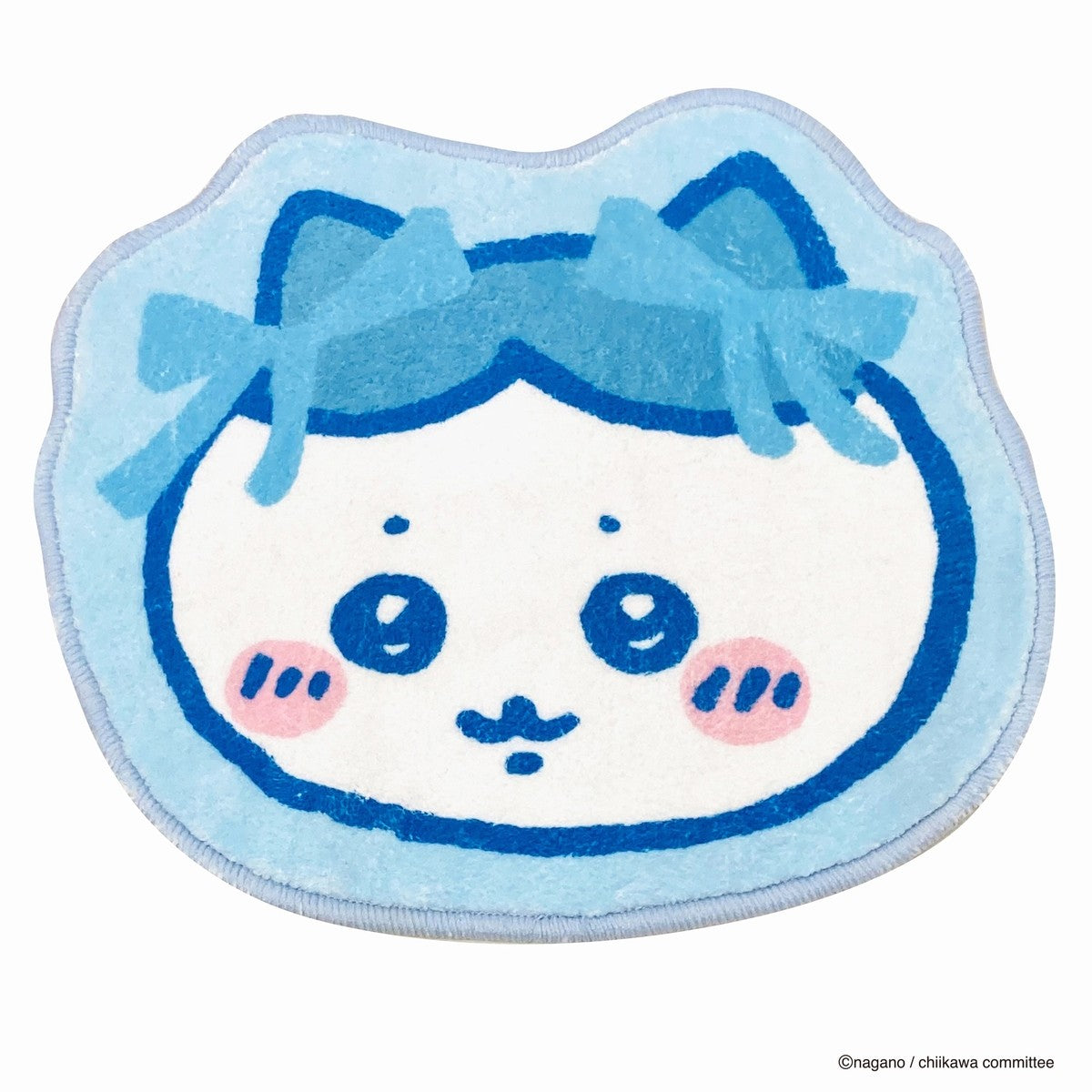 A light-blue character-shaped floor mat depicting a round face with rosy cheeks and two bows.