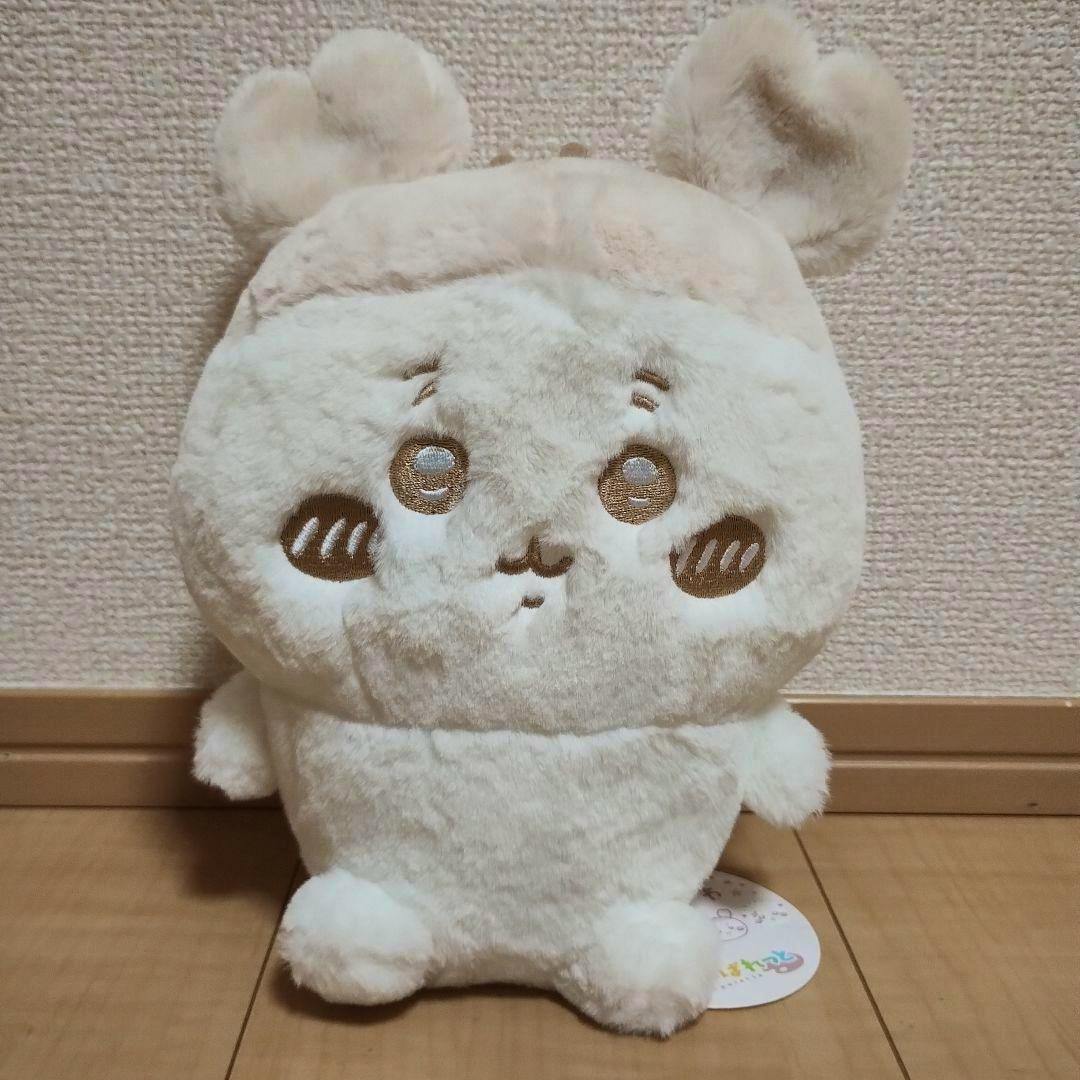 Front view of the cream-colored Chiikawa plush toy with embroidered face sitting on a wooden floor.