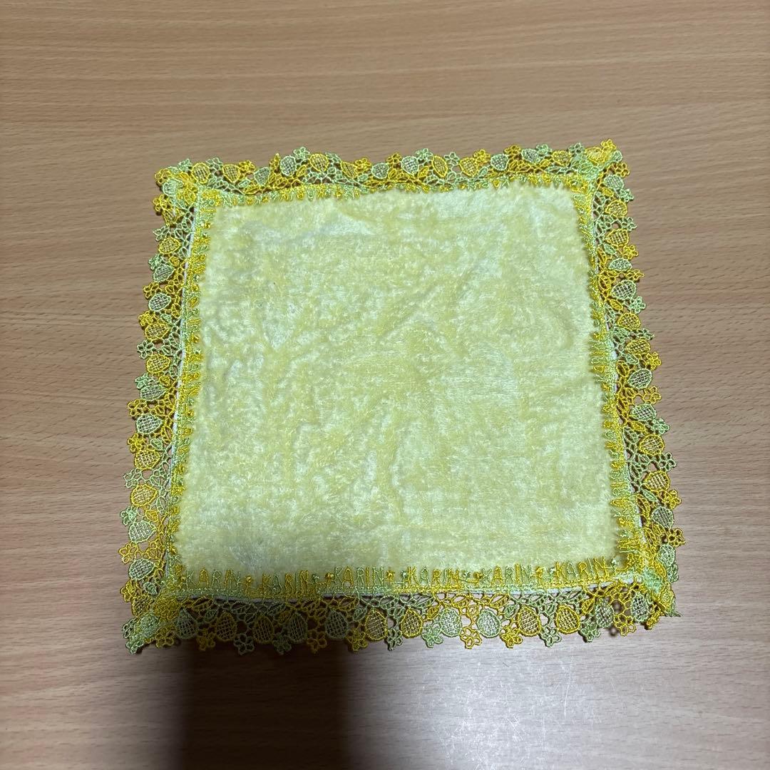 A yellow polyester handkerchief with decorative yellow lace border laid flat on a wooden surface.