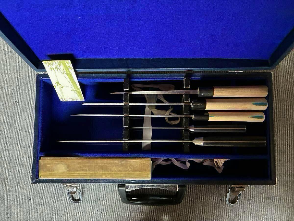 Open blue-lined case holding five knives with wooden handles and a whetstone.