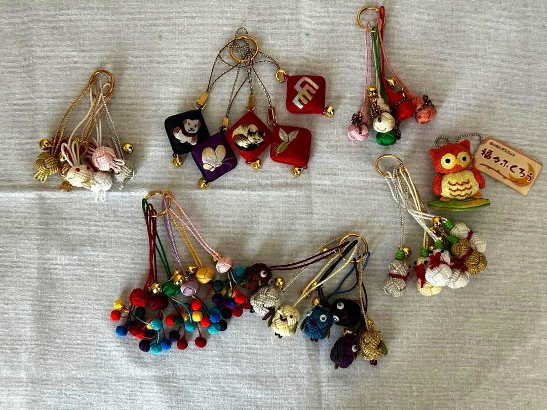 Several chirimen fabric netsuke-style keychain straps and small charms arranged on a light cloth background.