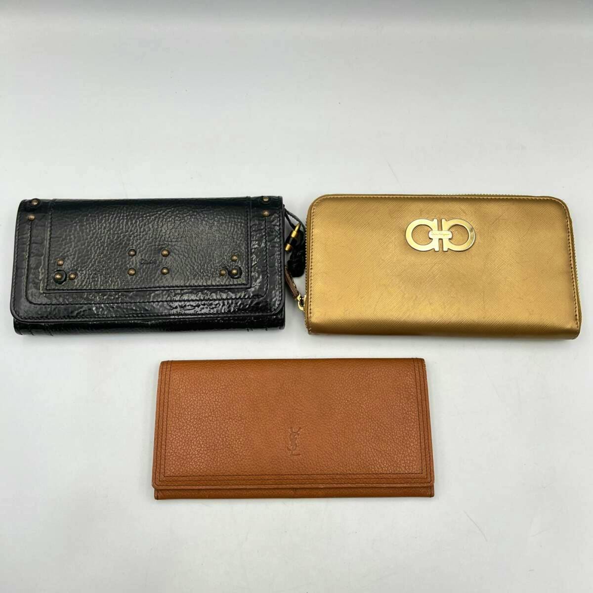 Three long wallets (black, gold zip-around, and brown) arranged on a white background.