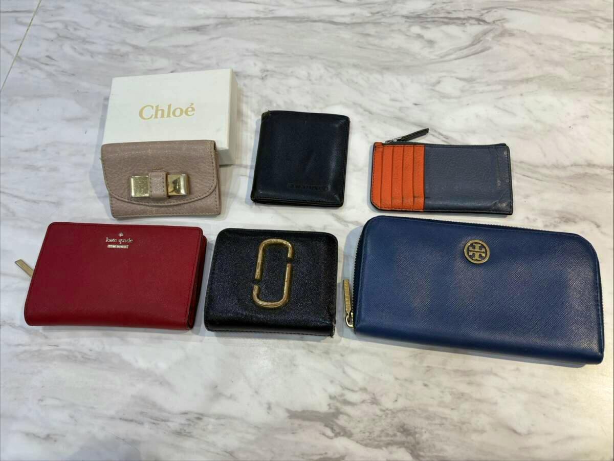 Six wallets and pass cases arranged on a marble surface.