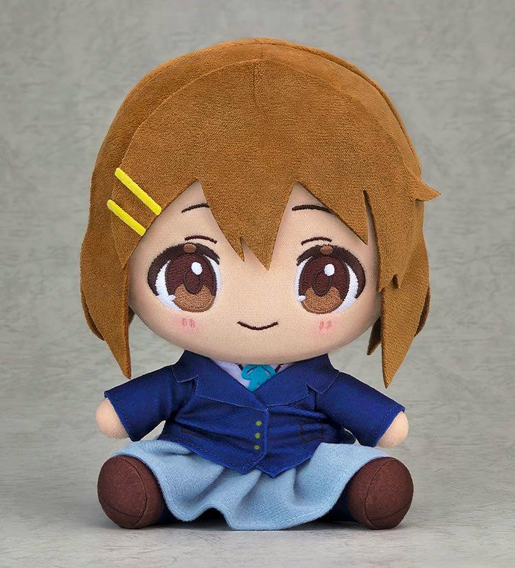 A seated chibi plush toy in a blue school uniform with brown hair and yellow hair clips.