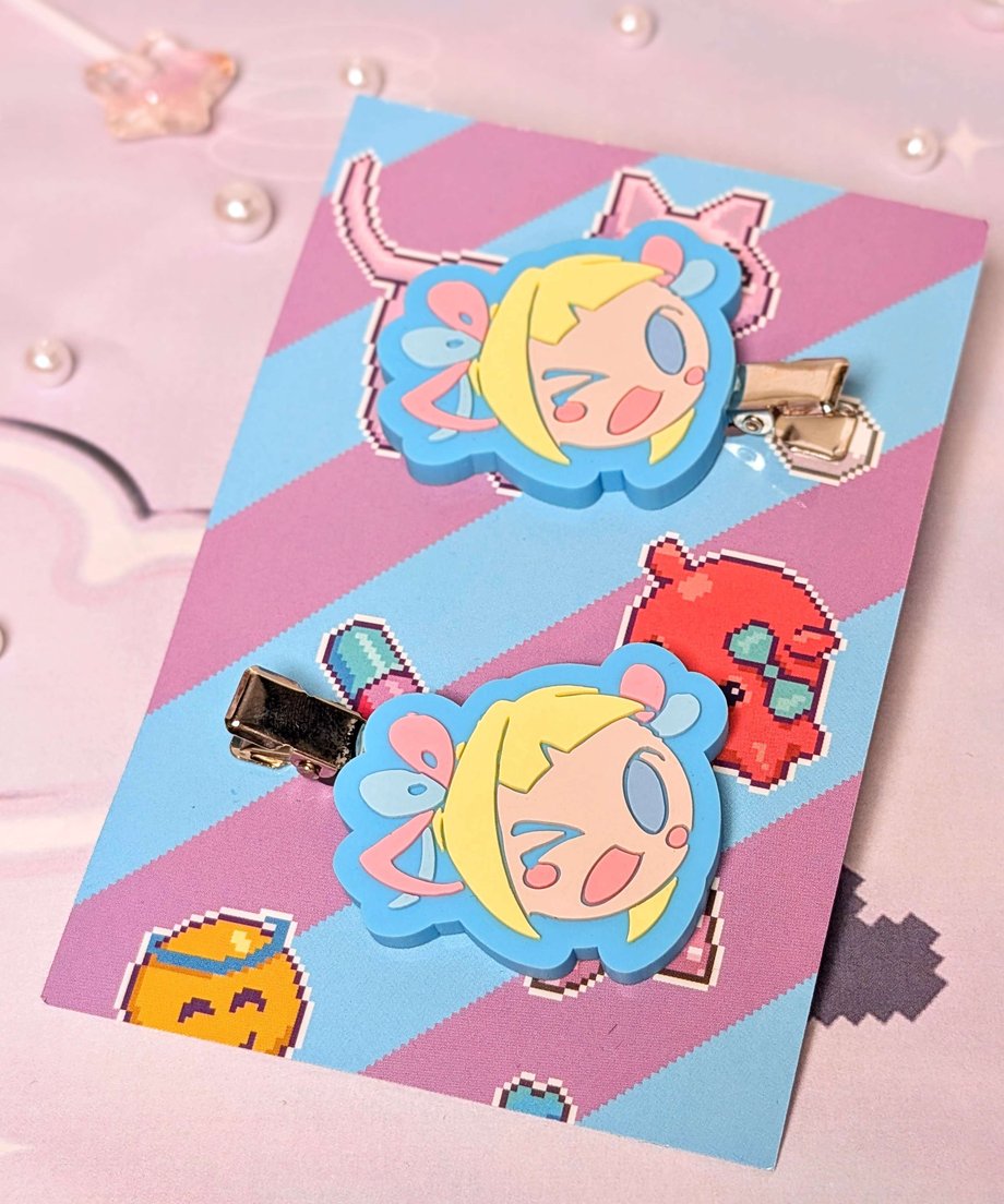 Two cartoon-face hair clips attached to a decorative backing card.