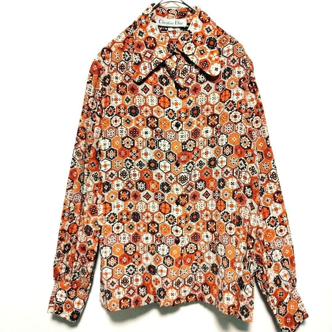 Front view of a men's long-sleeve silk shirt with an all-over retro hexagonal pattern in orange and brown, hanging on a hanger.