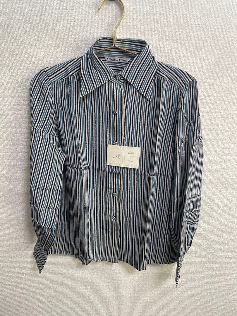 Long-sleeve men's silk striped shirt hanging on a hanger against a white wall.