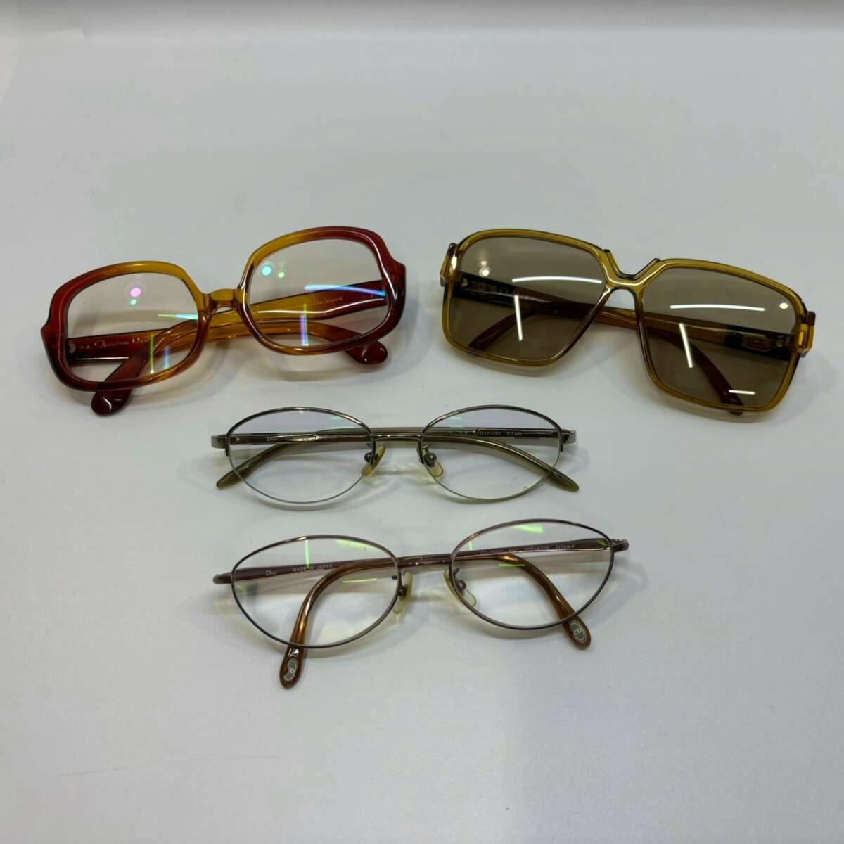 Four pairs of Christian Dior eyeglasses and sunglasses in brown tones laid flat on a white surface.