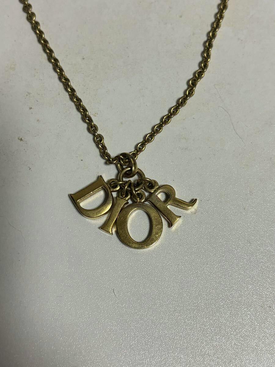 Close-up of a gold-tone Christian Dior necklace showing D, I, O, R letter charms on a chain.