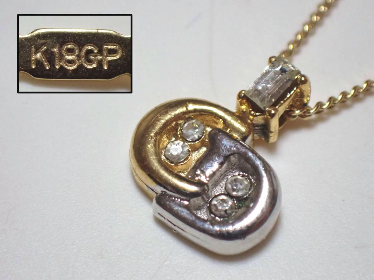 Close-up of the Christian Dior necklace showing the two-tone pendant with three small stones and an inset "K18GP" marking.