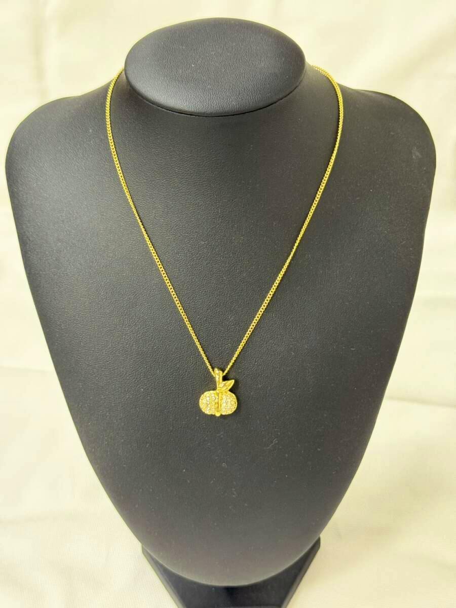 Christian Dior apple-motif gold-tone necklace with rhinestone pendant displayed on a black jewelry bust.