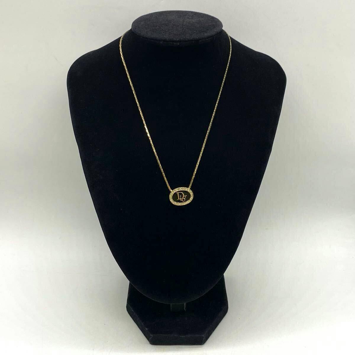 Gold-color Christian Dior necklace with an oval black plate surrounded by rhinestones displayed on a black mannequin bust.