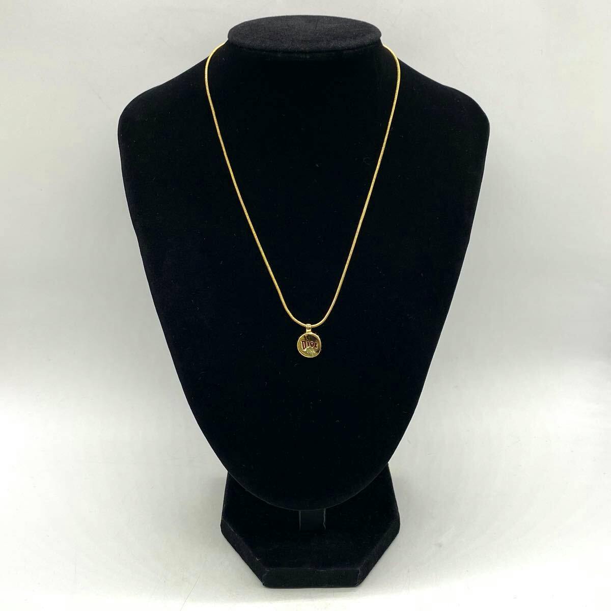 Gold-colored bottle-cap motif Christian Dior necklace displayed on a black jewelry bust.