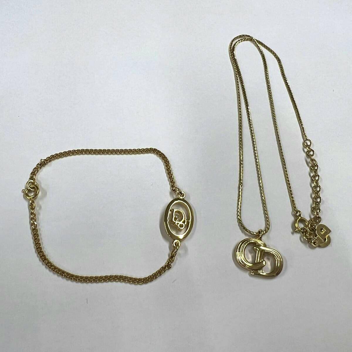 Gold-colored Christian Dior necklace and bracelet laid flat on a white background.