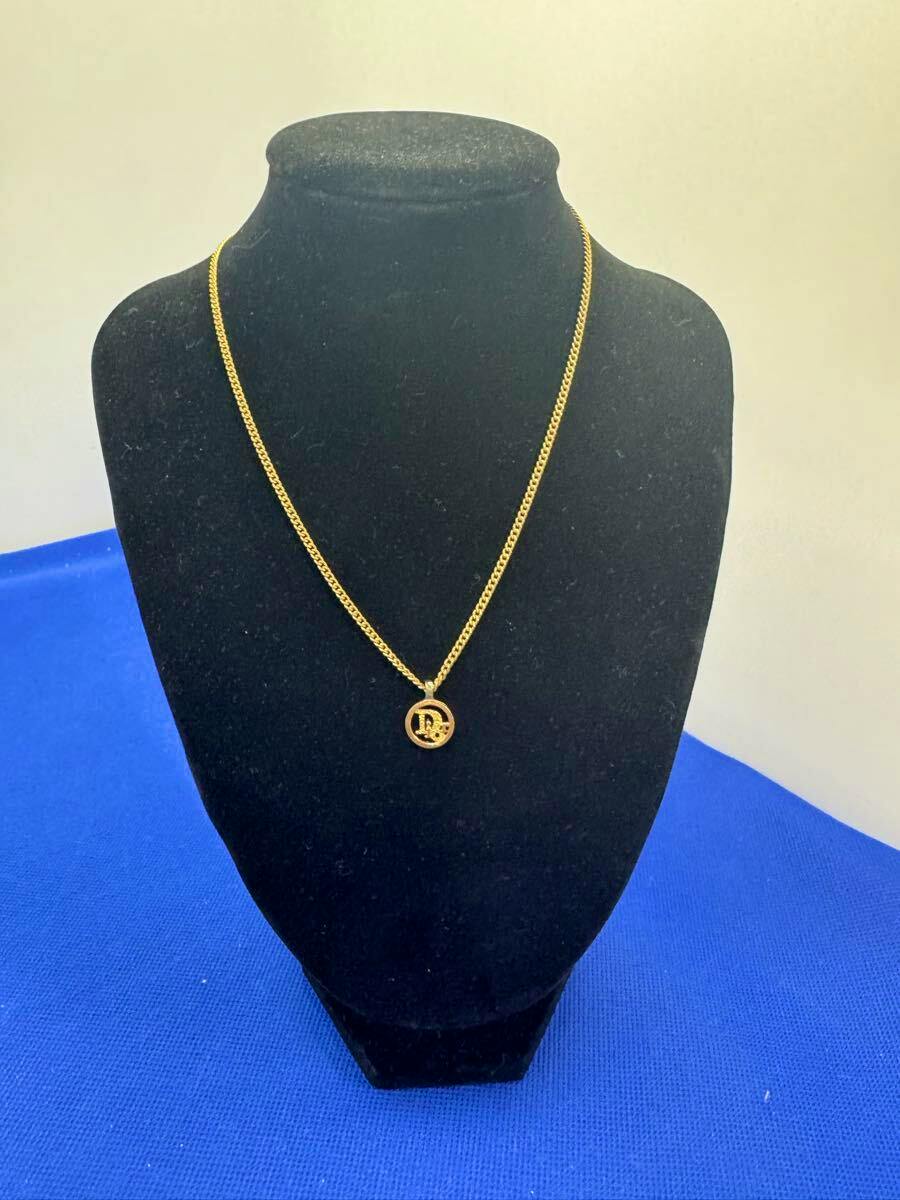 Gold Christian Dior CD logo circle necklace shown on a black display bust.