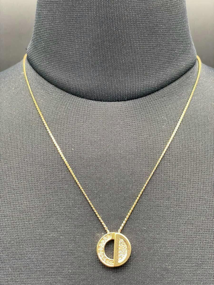 Christian Dior gold necklace with a circular CD-logo rhinestone pendant displayed on a black mannequin bust.