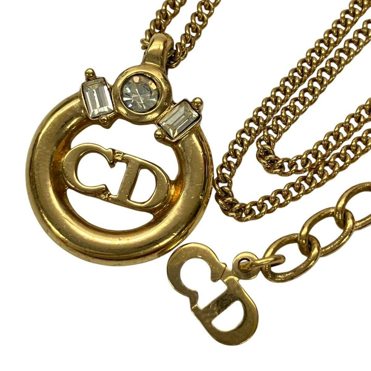 Gold-tone Christian Dior necklace pendant featuring a circular CD logo and three stones shown with its chain.