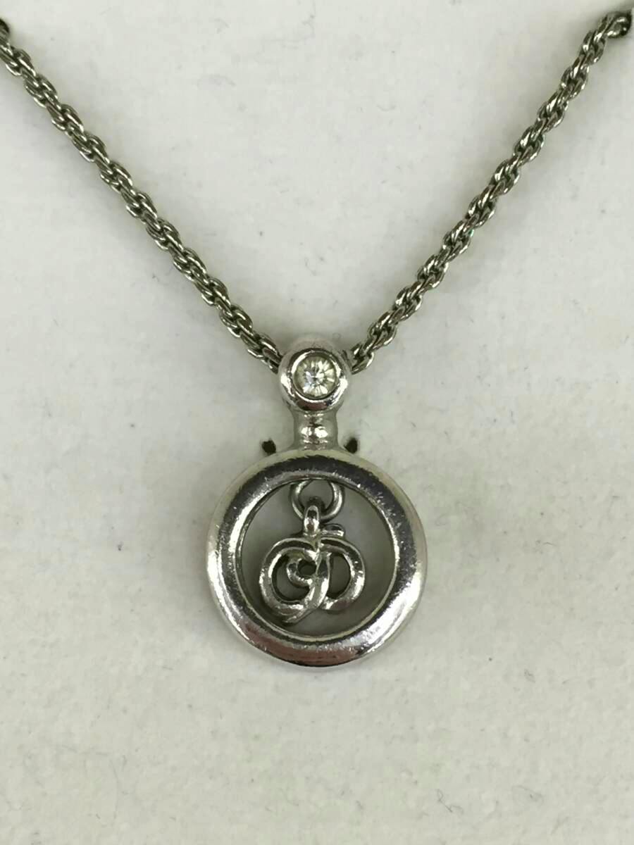 Close-up of a silver-coloured circular pendant with small interlocking CD logo on a chain against a white background.