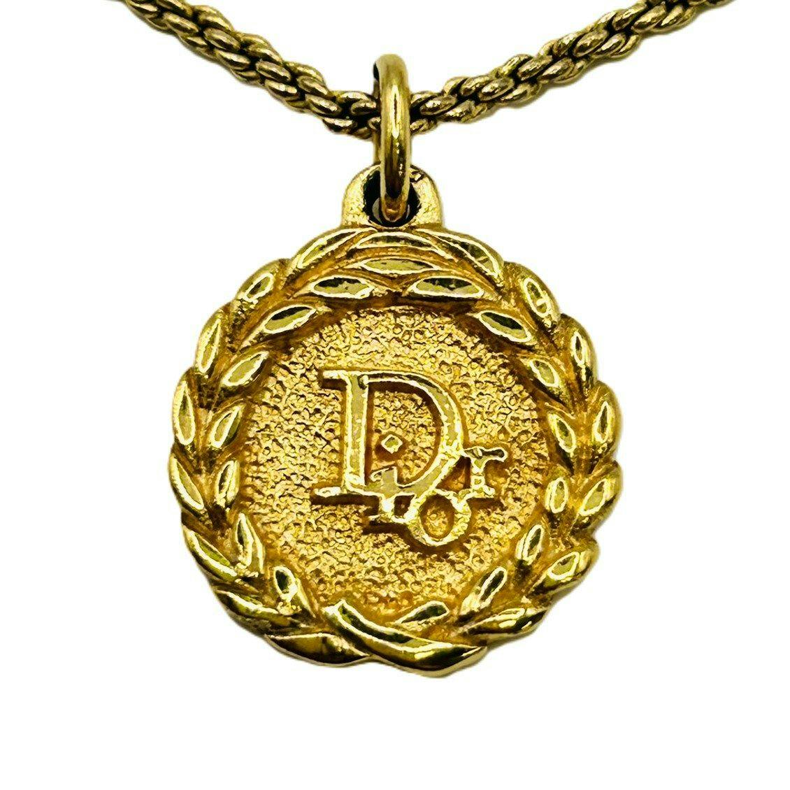 Close-up of the Christian Dior CD logo coin-top pendant on a gold-tone necklace chain.