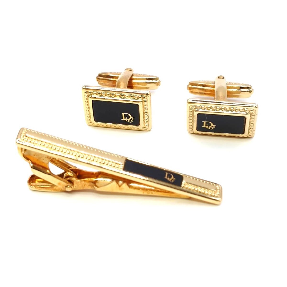 Gold and black Christian Dior tie clip with matching cufflinks shown on a white background.