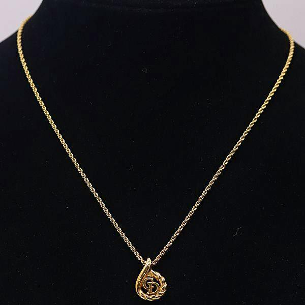 Christian Dior gold-color CD logo drop-motif necklace displayed on a black jewelry bust.