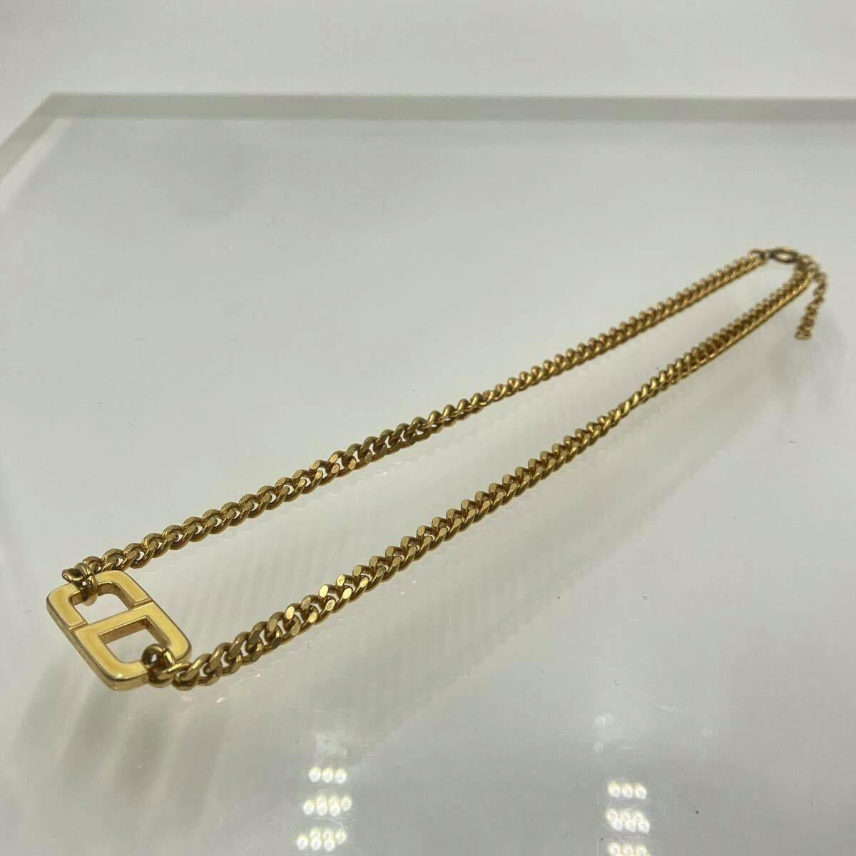 Gold-color Christian Dior CD-logo curb chain necklace laid flat on a white surface.