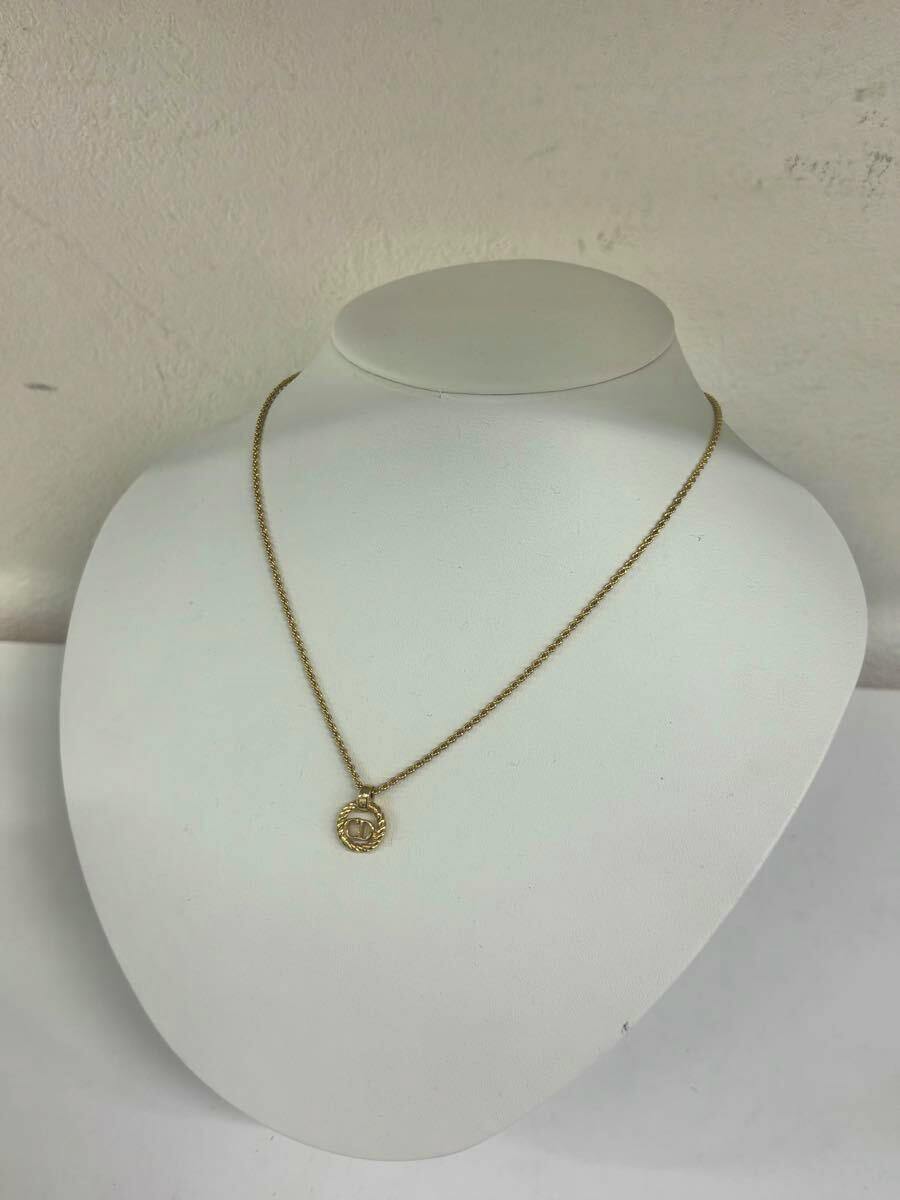 Gold-colored Christian Dior necklace with a circular CD logo pendant displayed on a white bust.
