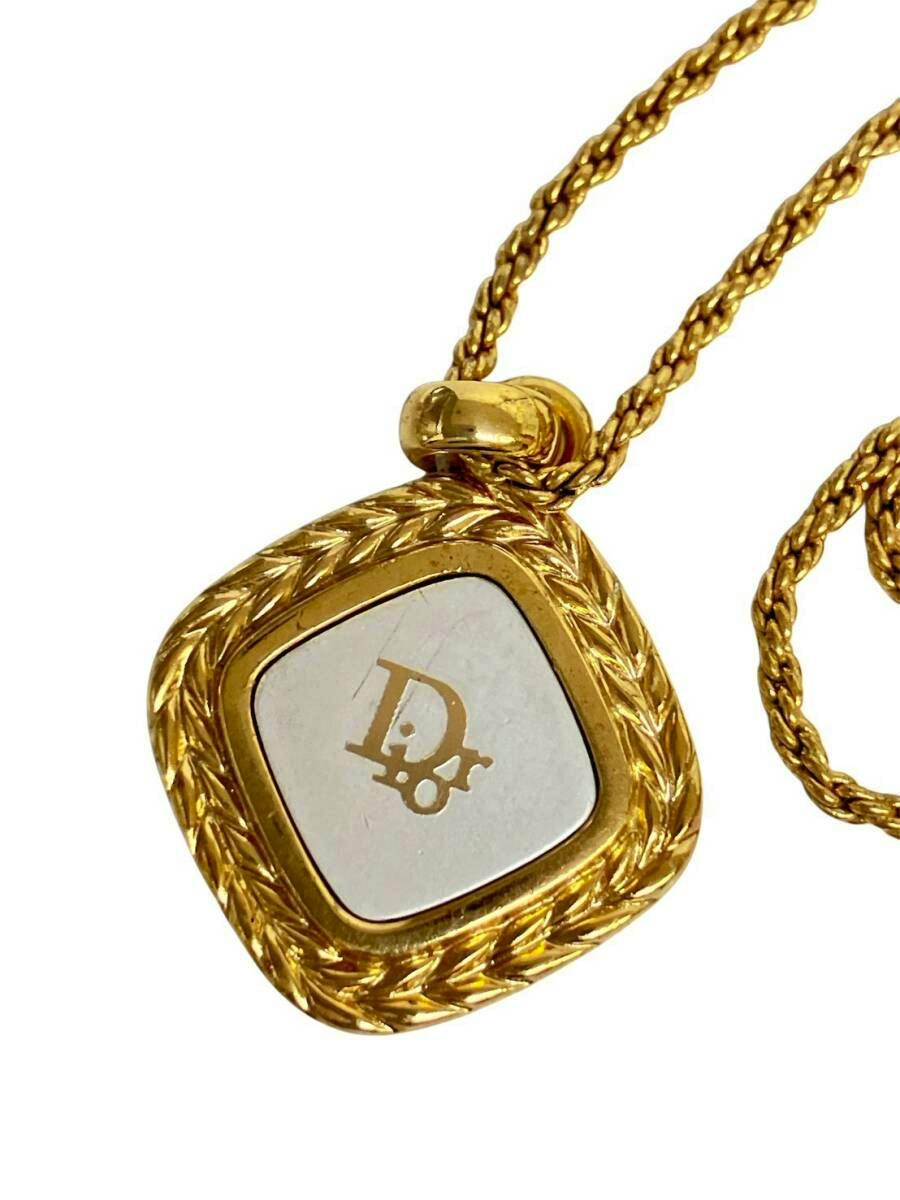 Close-up of a gold-colored Christian Dior necklace pendant showing a square sculpted frame and CD logo on the center plate.