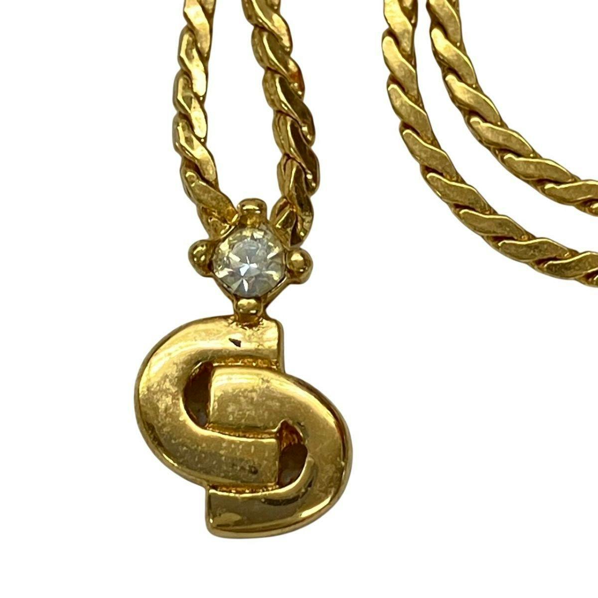Close-up of the gold-color Christian Dior CD-logo necklace pendant with a clear stone and twisted chain.