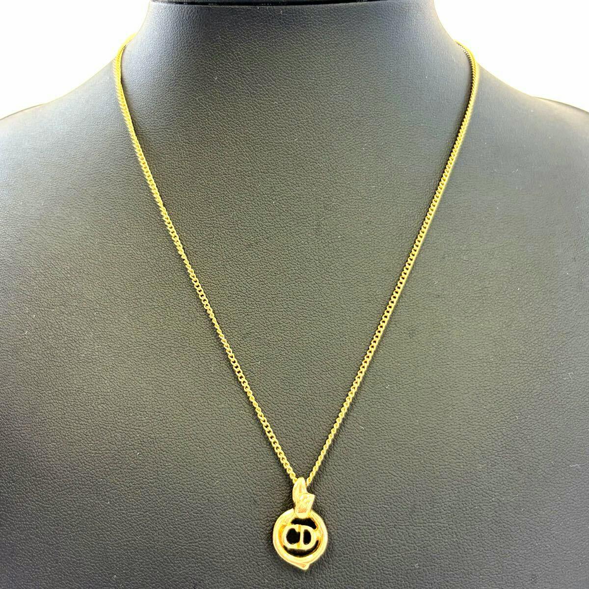 Gold-colored Christian Dior CD logo necklace with pendant displayed on a black mannequin bust.
