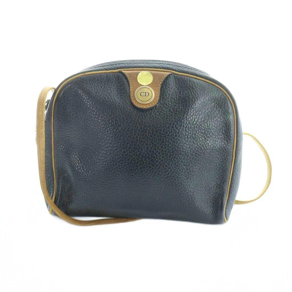 Front view of a navy Christian Dior leather shoulder bag with tan piping, a circular CD logo plate, and a strap.