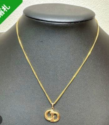 Gold-tone Christian Dior CD logo necklace displayed on a black jewelry bust.