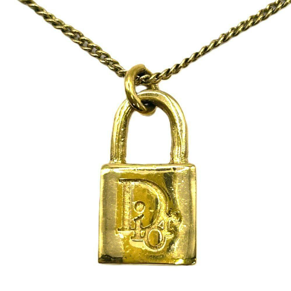 Close-up of a gold-tone padlock pendant engraved with a CD logo hanging from a thin chain.