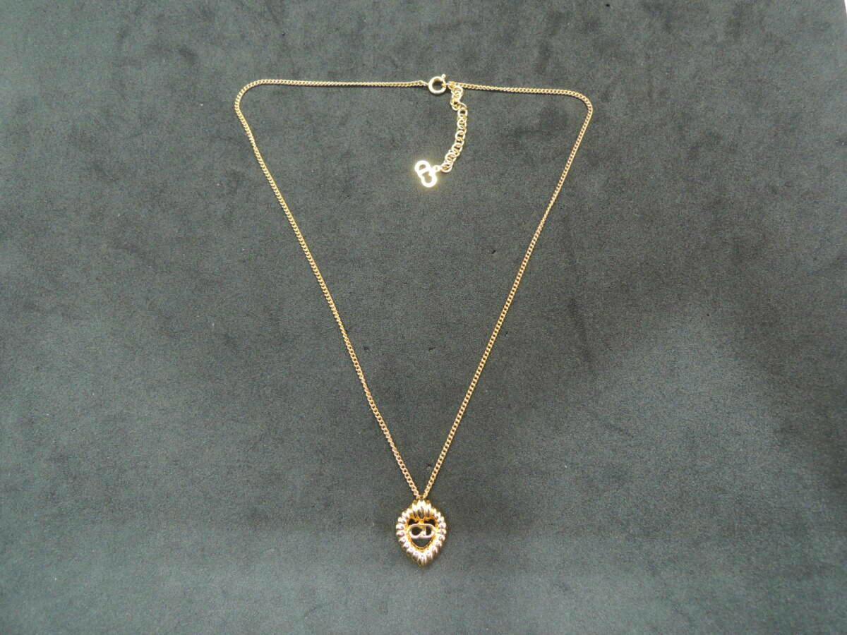 Christian Dior gold-tone pendant necklace with CD logo laid flat on a black background.