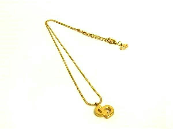 Gold-tone necklace with a CD logo pendant laid flat on a white background.