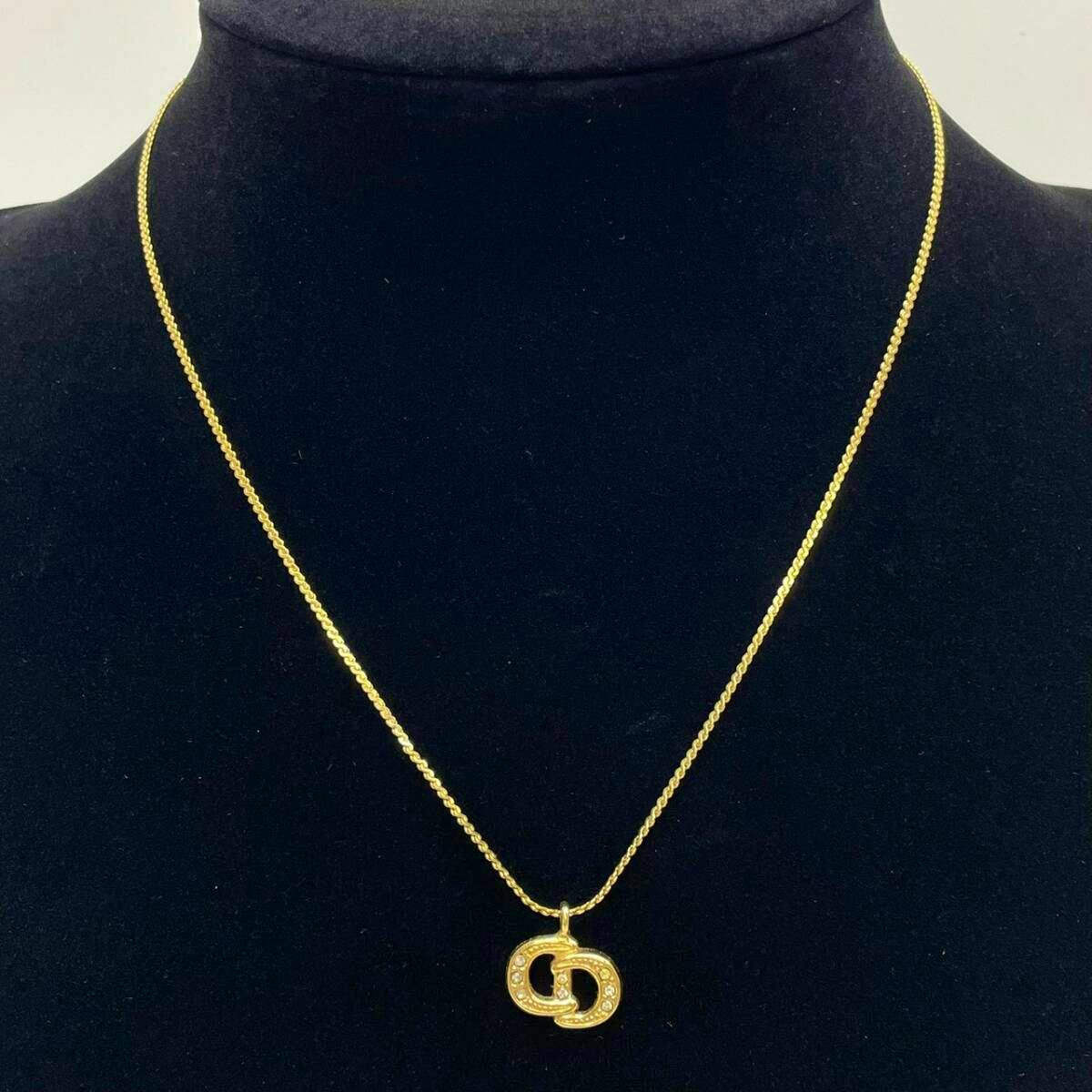 Gold-color Christian Dior necklace with an interlocking CD logo pendant set with rhinestones displayed on a black bust.