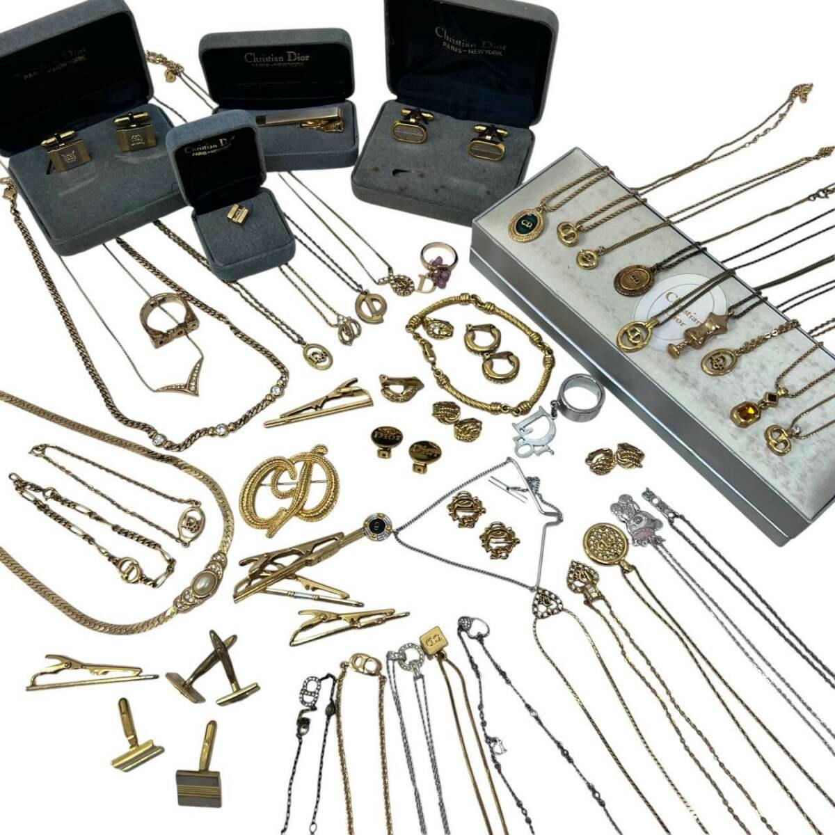 Assorted Christian Dior necklaces, brooches, cufflinks and other gold- and silver-tone jewelry pieces laid out on a white surface.