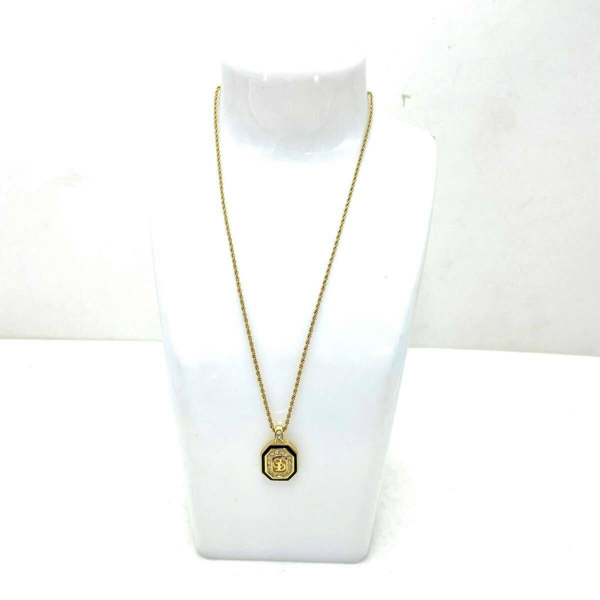 Gold-tone Christian Dior necklace with an octagonal pendant featuring a CD logo displayed on a white bust.