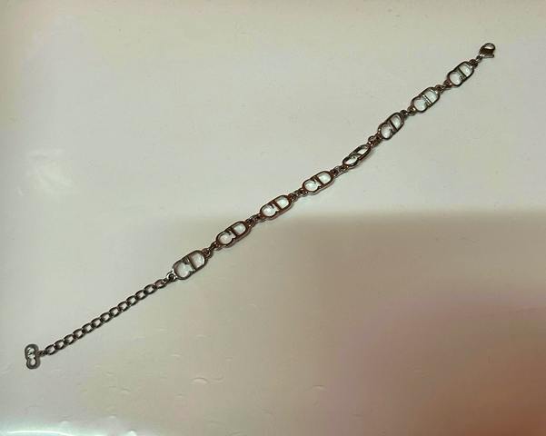 Silver-colored Christian Dior bracelet with CD-logo style links laid flat on a white surface.